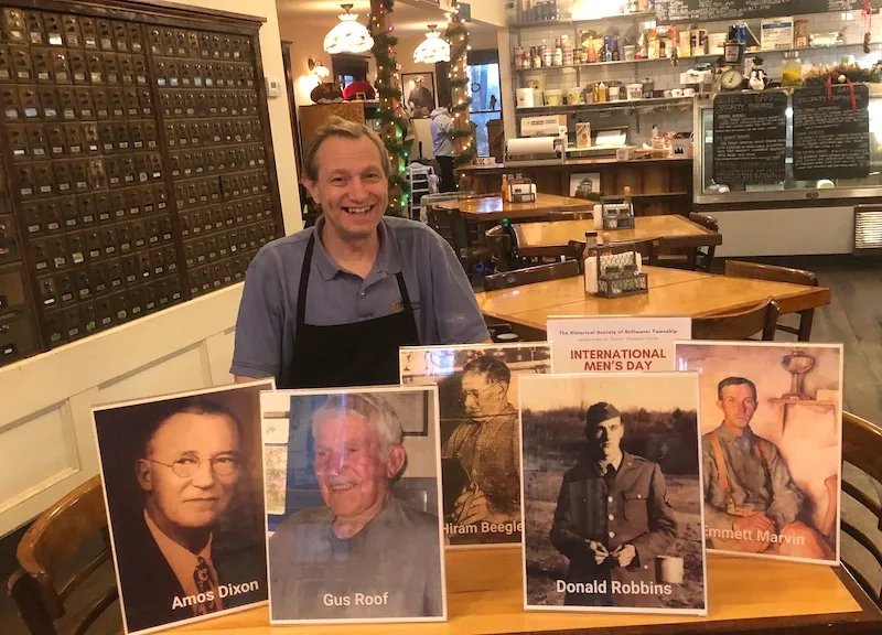 Dave Glueck, new owner of the general store in Stillwater, with the photos displayed for International Men's Day.